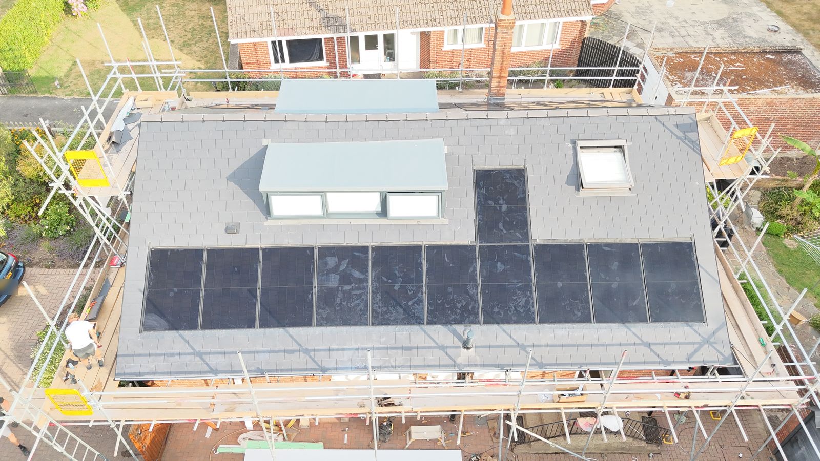 In-roof solar panels fitted flush with new grey slates, scaffold still up, Canterbury