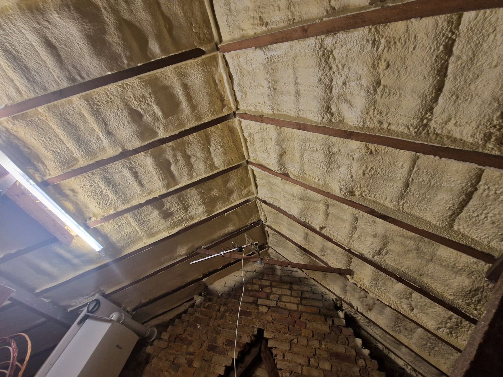 Spray foam insulation applied between and over the rafters inside a loft near Sittingbourne